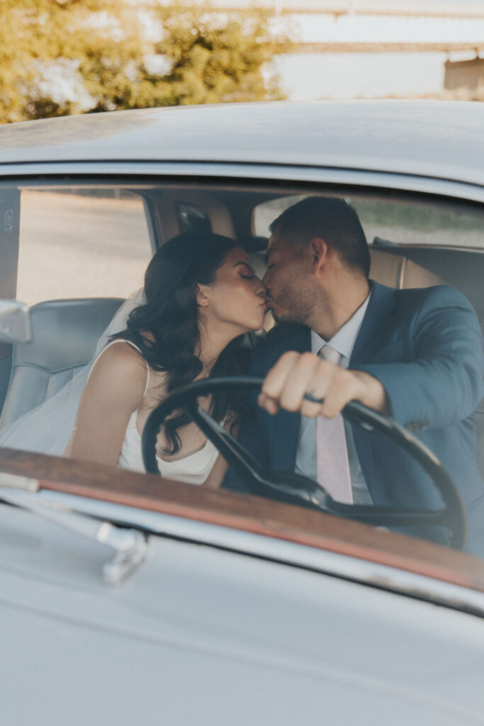 Bride and groom kissing in vintage car