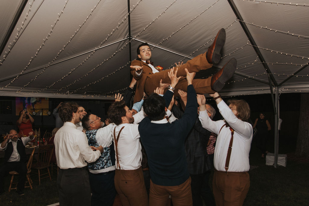 Groom being lifted up by groomsmen