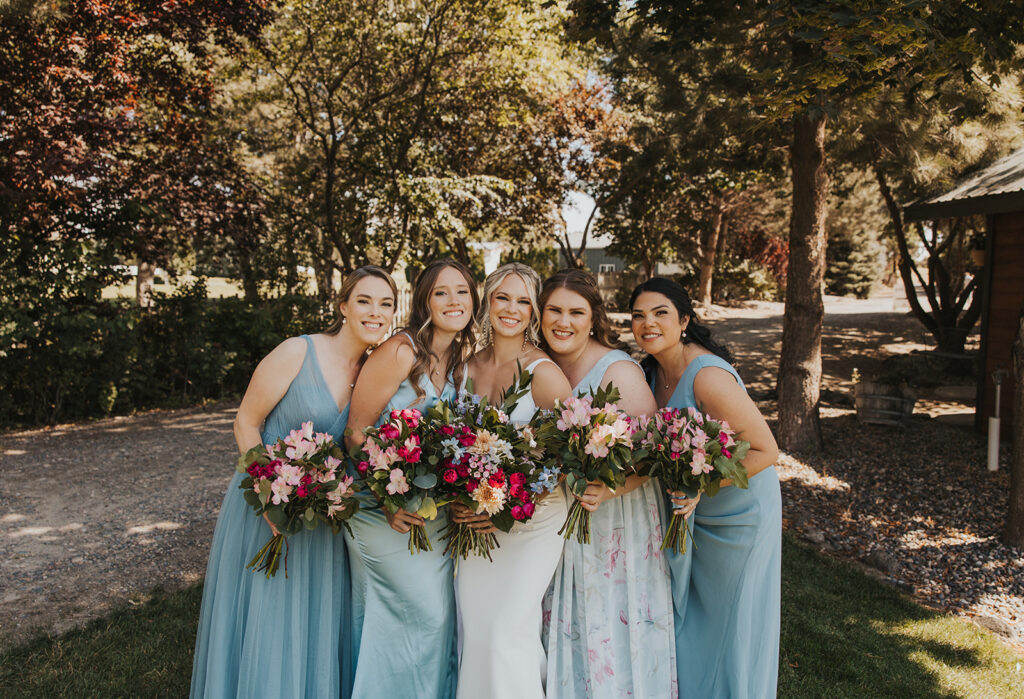 Bride and bridesmaids, bridesmaids wearing blue mismatched bridesmaids dresses