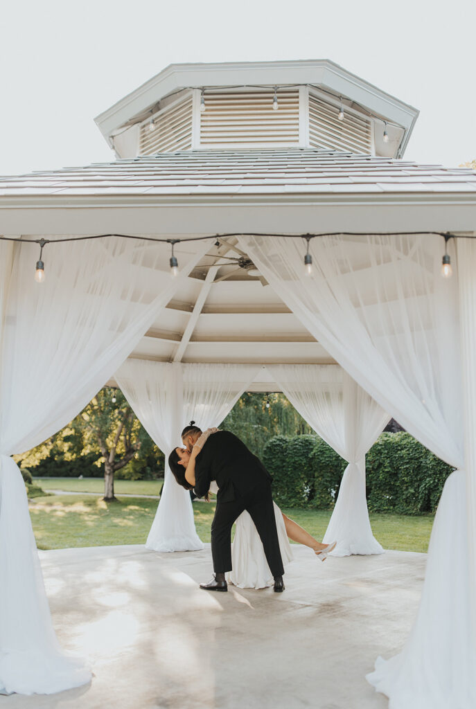 bride and groom first dance in a white gazebo