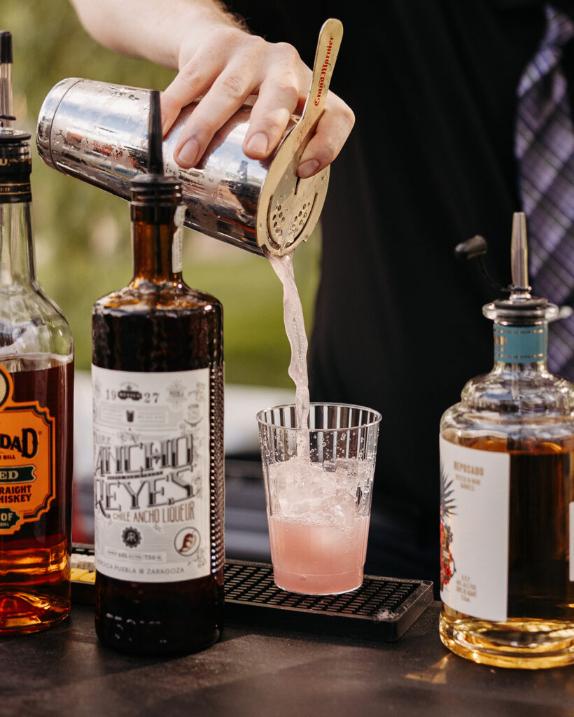 A bartender pouring drinks at an outdoor wedding reception