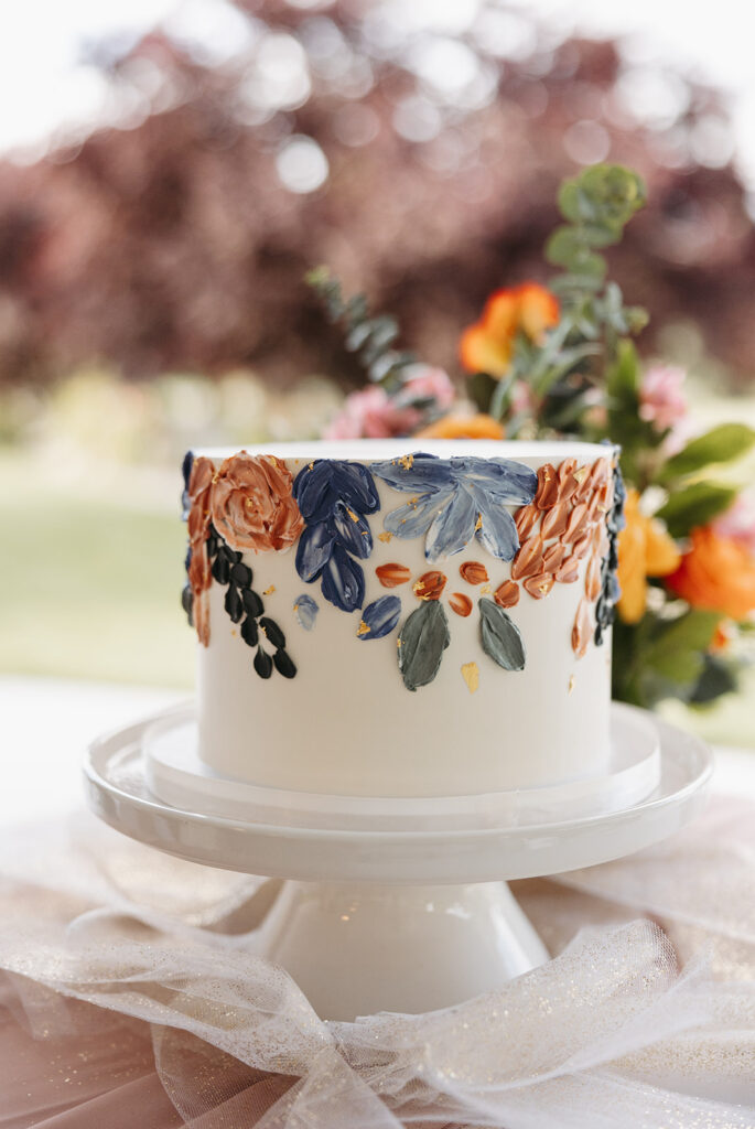 White wedding cake with painted floral and greenery details