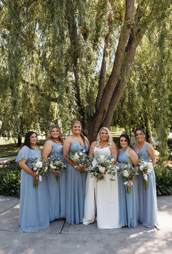 Samantha and her bridesmaids, all smiles, standing together in the garden before the ceremony.