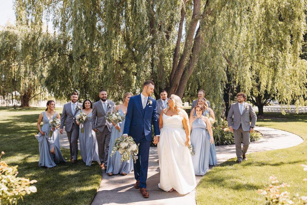 A wide shot of the wedding party walking in the Promise Garden.
