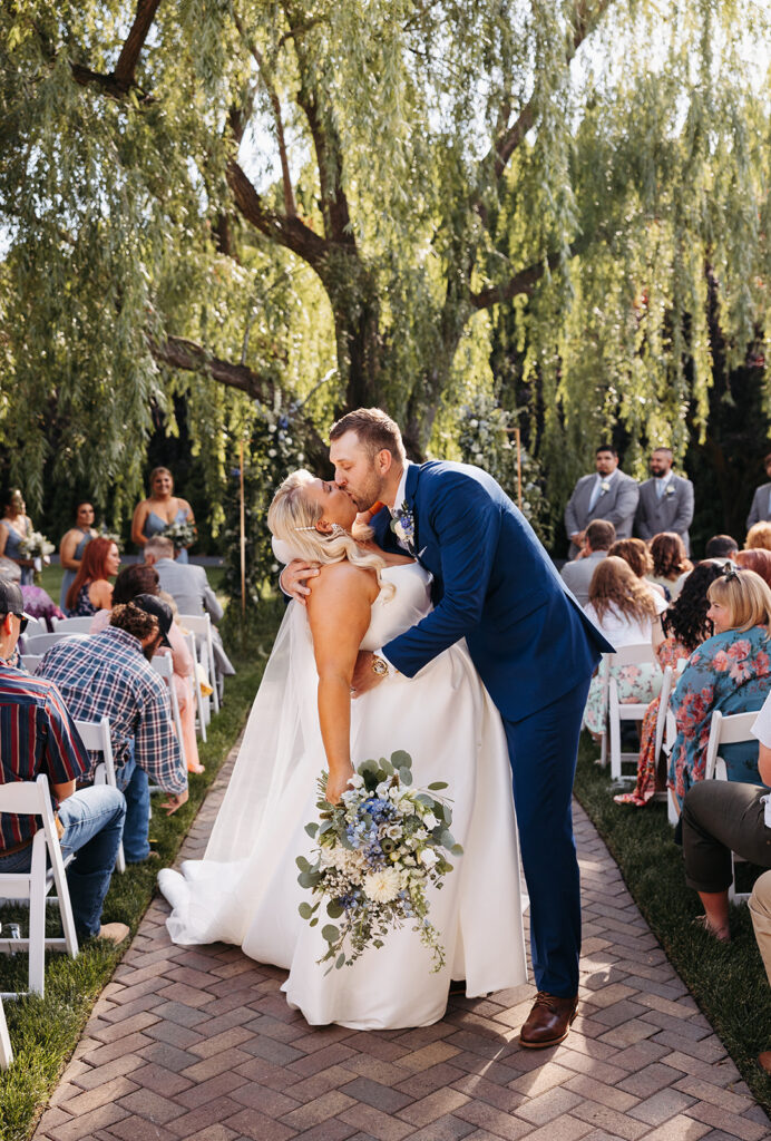 Bride and groom dip and kiss in the aisle after their Promise Garden wedding ceremony