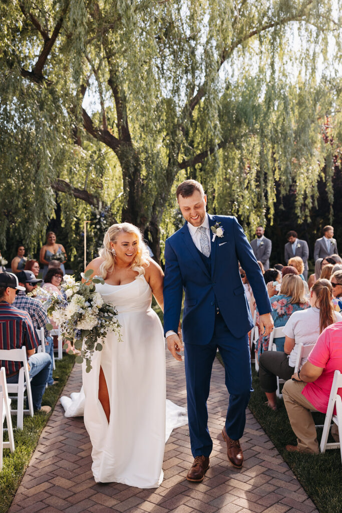 The couple walking hand-in-hand through the Promise Garden, framed by vibrant flowers.