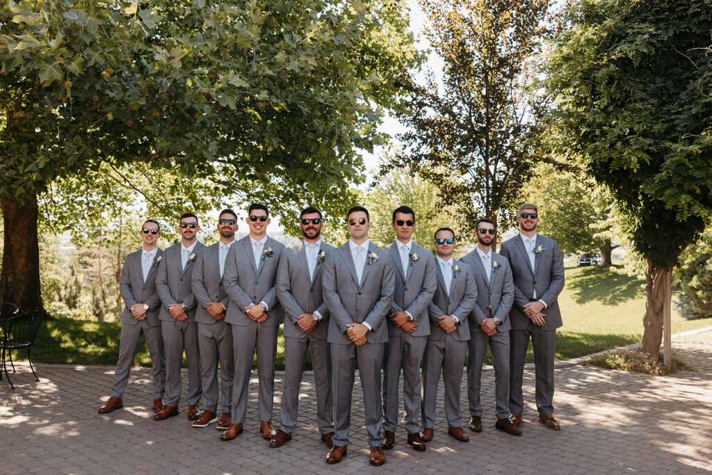 Groomsmen stand at Terra Blanca Winery, with the scenic greenery providing a perfect backdrop.