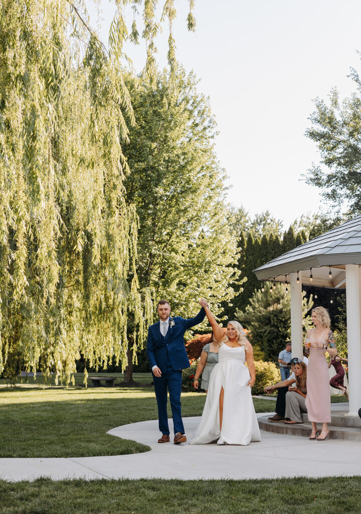 Bride and groom walk into the Promise Garden wedding reception space as husband and wife