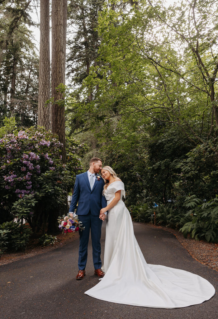 Bride and groom standing on a forested pathway near Kiana Lodge in Poulsbo, WA