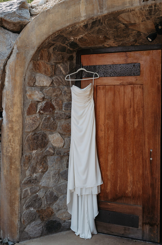 Bride wedding gown hanging in a stone doorway