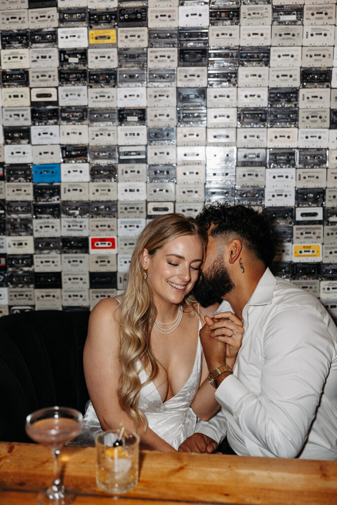 Couple sits playfully in a bar booth during their engagement photo session