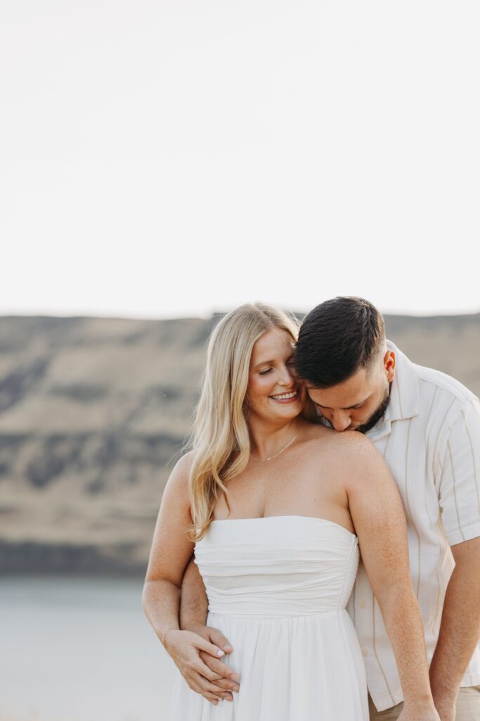 Couple sharing a close moment outdoors during an engagement session, photographed in a warm editorial wedding photography style by Kat Nielsen Photography