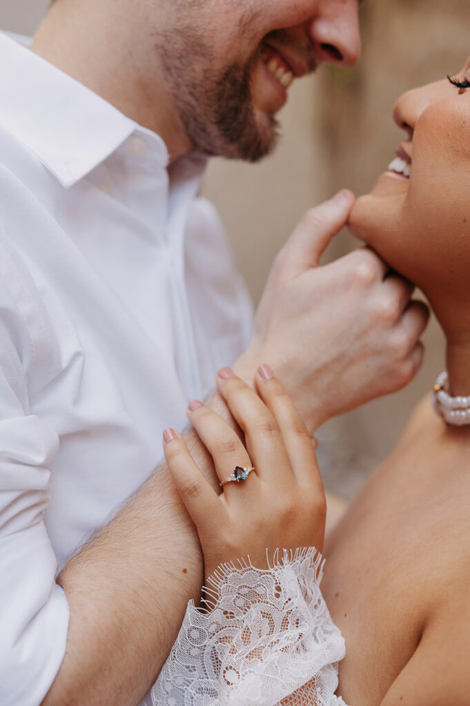 Close-up of a couple sharing an intimate moment, the bride’s hand resting on the groom’s arm, highlighting a natural gesture and engagement ring during a candid interaction.