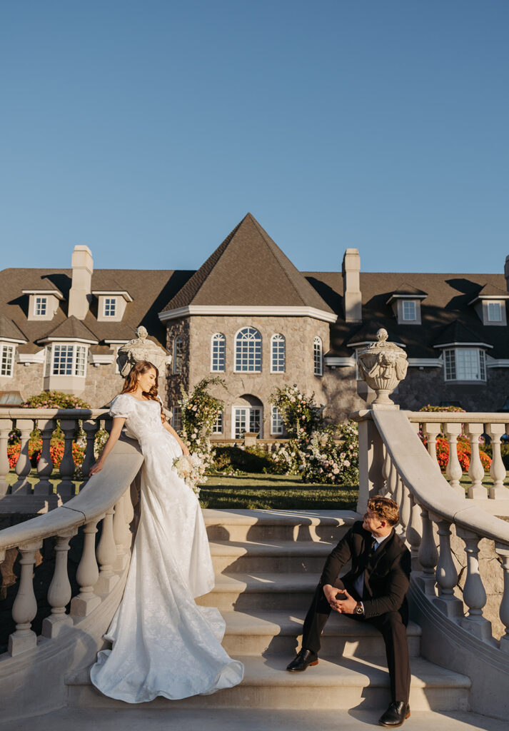 Bride and groom posed on stone steps at Chateau de Michellia, framed by grand architecture and soft floral installations.
