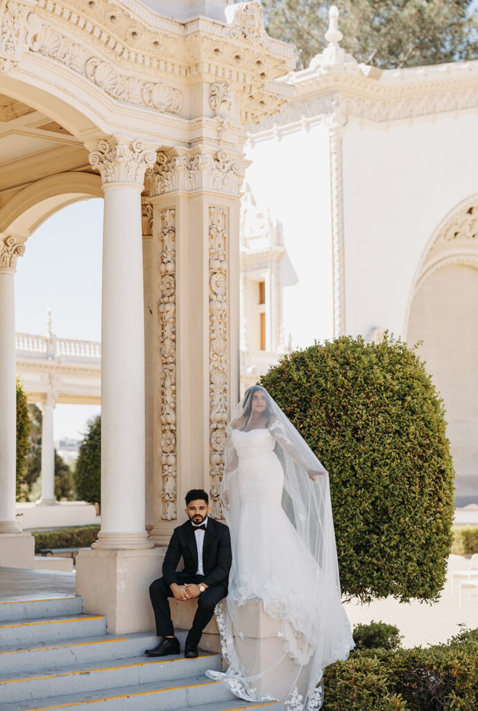 Bride and groom posed near ornate architectural columns, photographed with a refined editorial wedding photography approach.