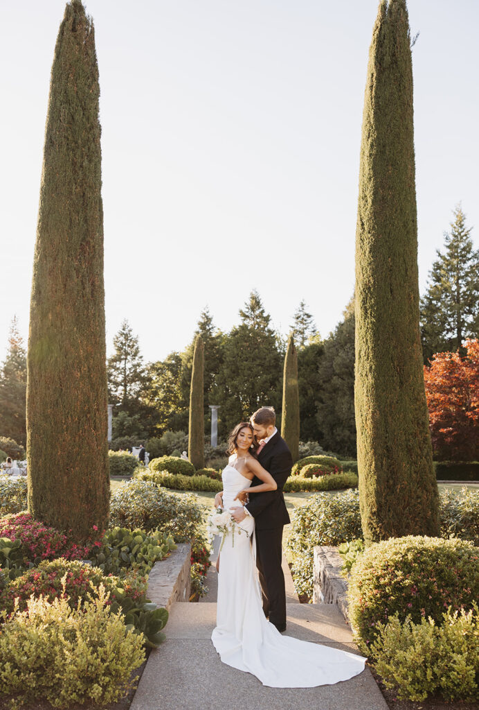 Bride and groom standing together in a formal garden, photographed with intentional editorial wedding photography.