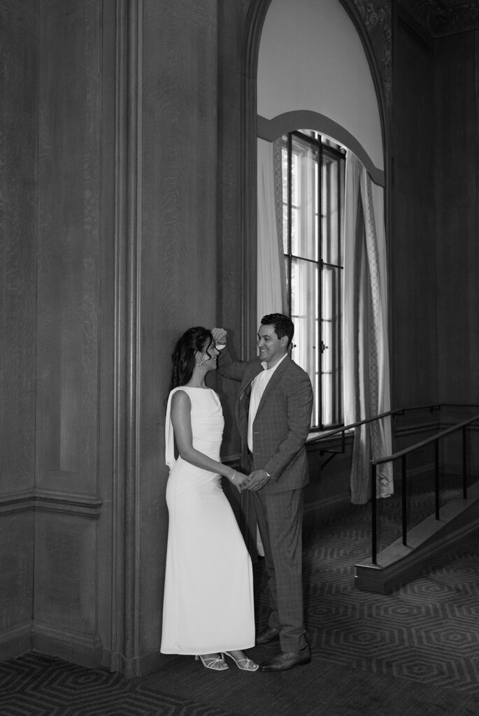 Black and white image of a couple standing together indoors, photographed with an editorial wedding photography perspective.