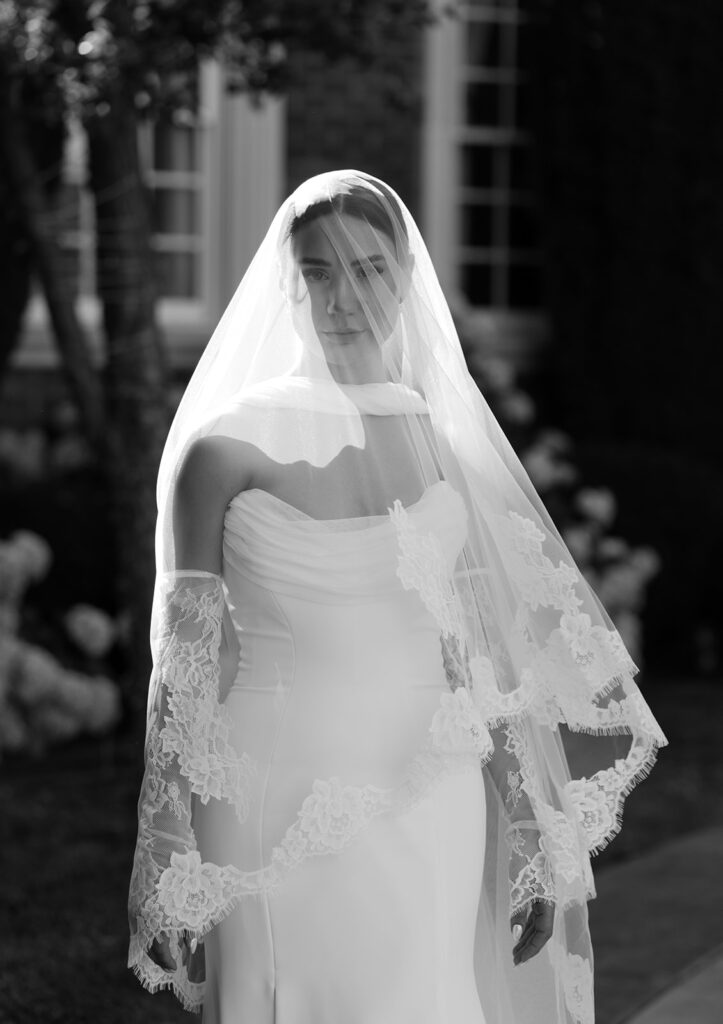 Black and white portrait of a bride wearing a veil, photographed in a timeless editorial wedding photography style.