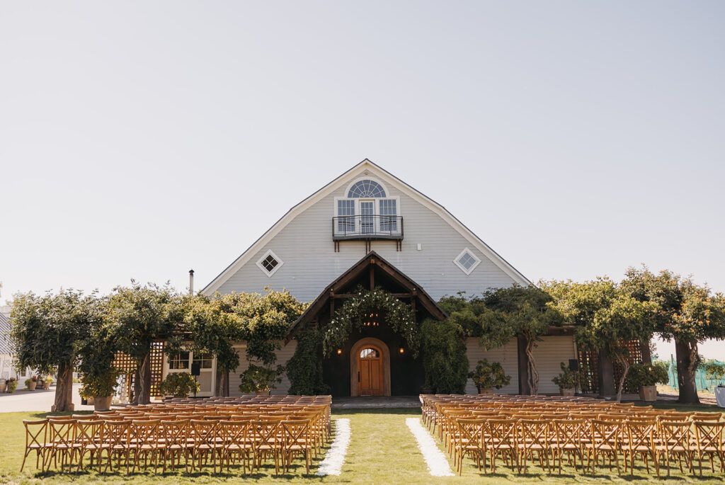 Luxury outdoor wedding ceremony at Abeja Winery in Walla Walla with vineyard views, wooden ceremony chairs, and refined barn architecture