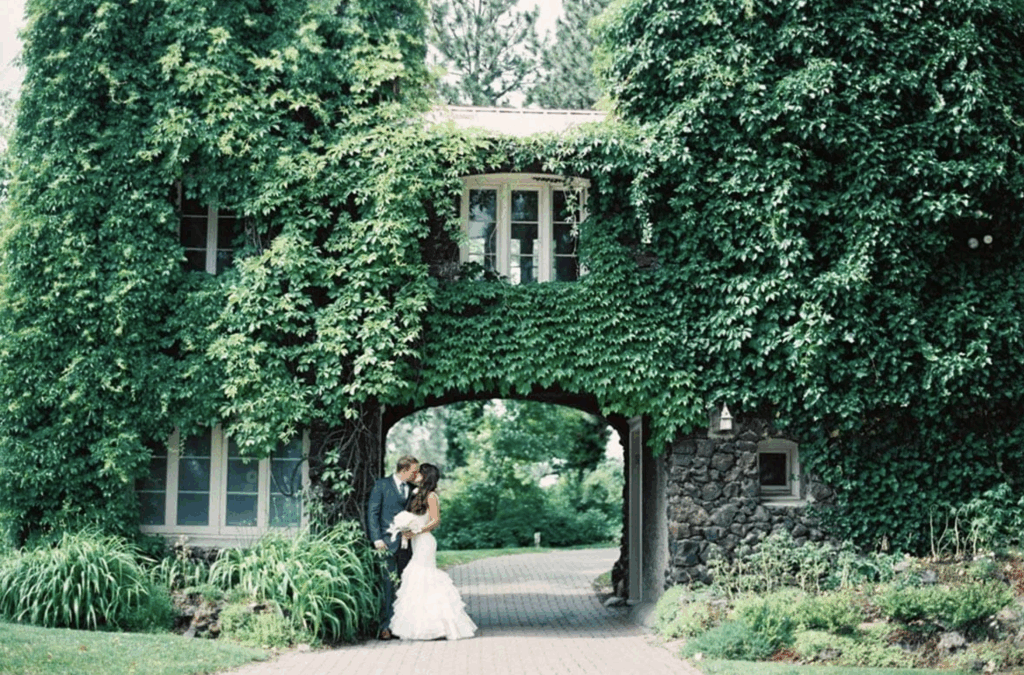 Bride and groom portrait beneath ivy-covered stone archway at Arbor Crest Wine Cellars in Spokane, Washington