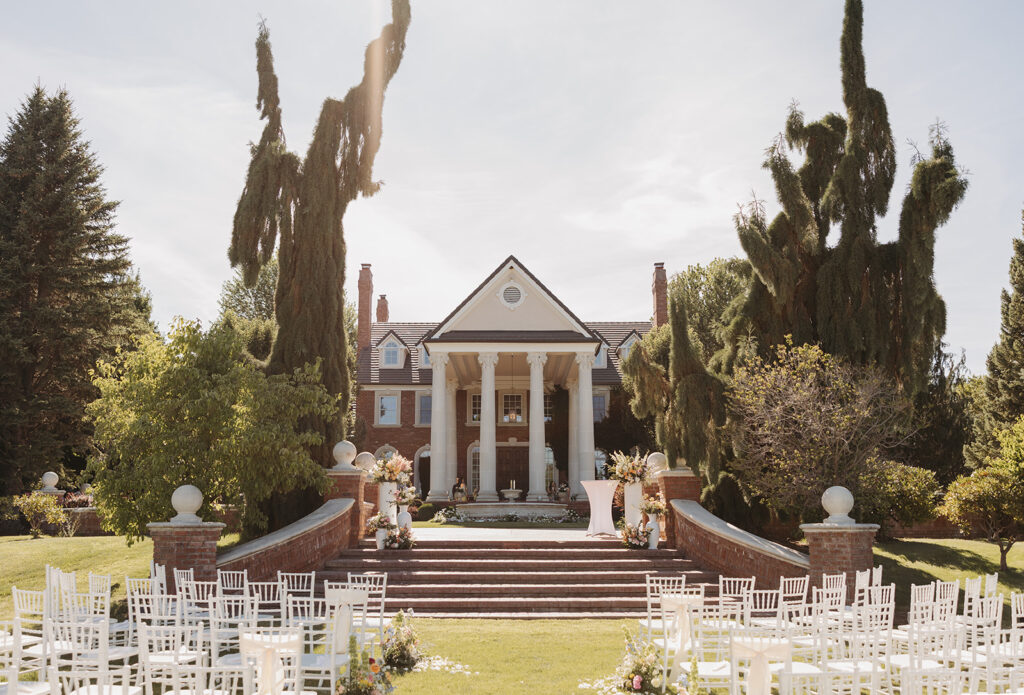 Luxury outdoor wedding ceremony at Oakshire Estate in the Pacific Northwest with a classic estate backdrop, white ceremony chairs, and refined floral design